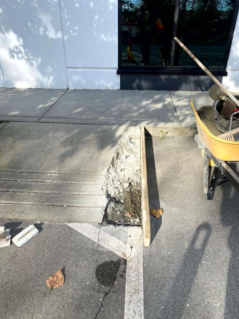 Concrete repair work is underway on a sidewalk edge near a window.